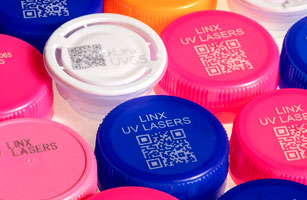 Linx UV laser mark encoder labels on colorful plastic caps.