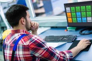High-tech industrial control system operator monitoring manufacturing automation on computer screen.